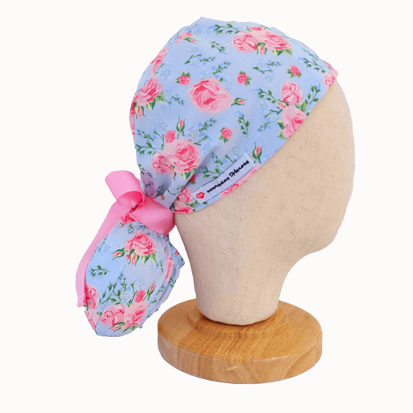 a mannequin head wearing a scrub cap ponytail for nurses ,with pink roses and a pink ribbon i tie