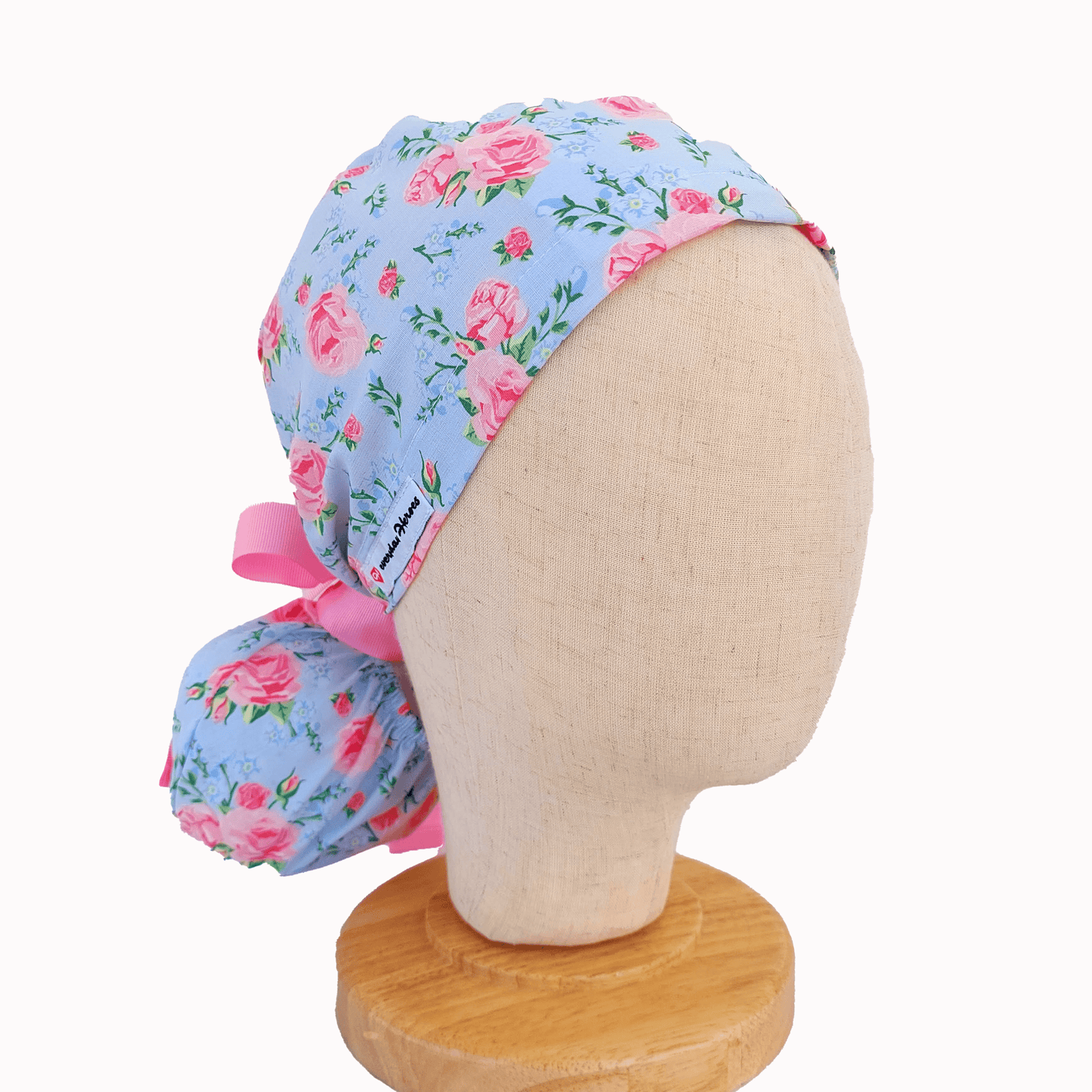 a mannequin head wearing a scrub cap ponytail for nurses ,with pink roses and a pink ribbon i tie
