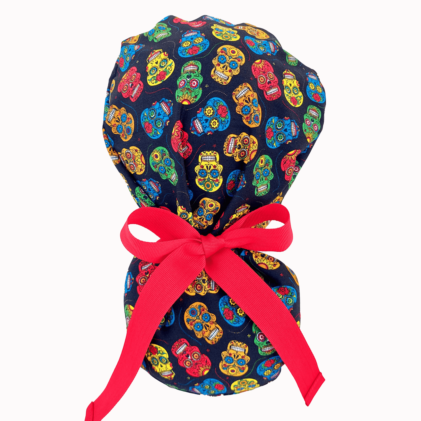 mannequin wearing a scrub cap ponytail with small colorful skulls and a separate pounch on it for the ponytail that hold the long hair and ties with red ribbons