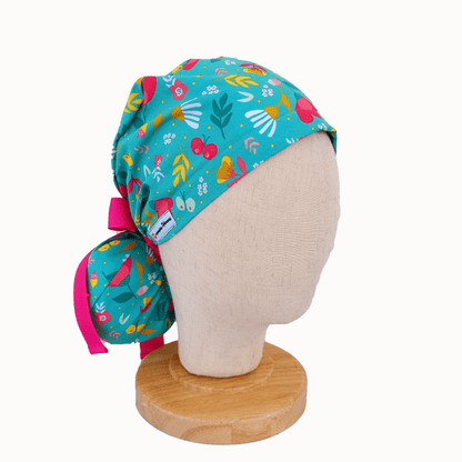 a mannequin head wearing a scrub cap ponytail for nurses ,with flowers and butterflies print  and a hot pink ribbon i tie