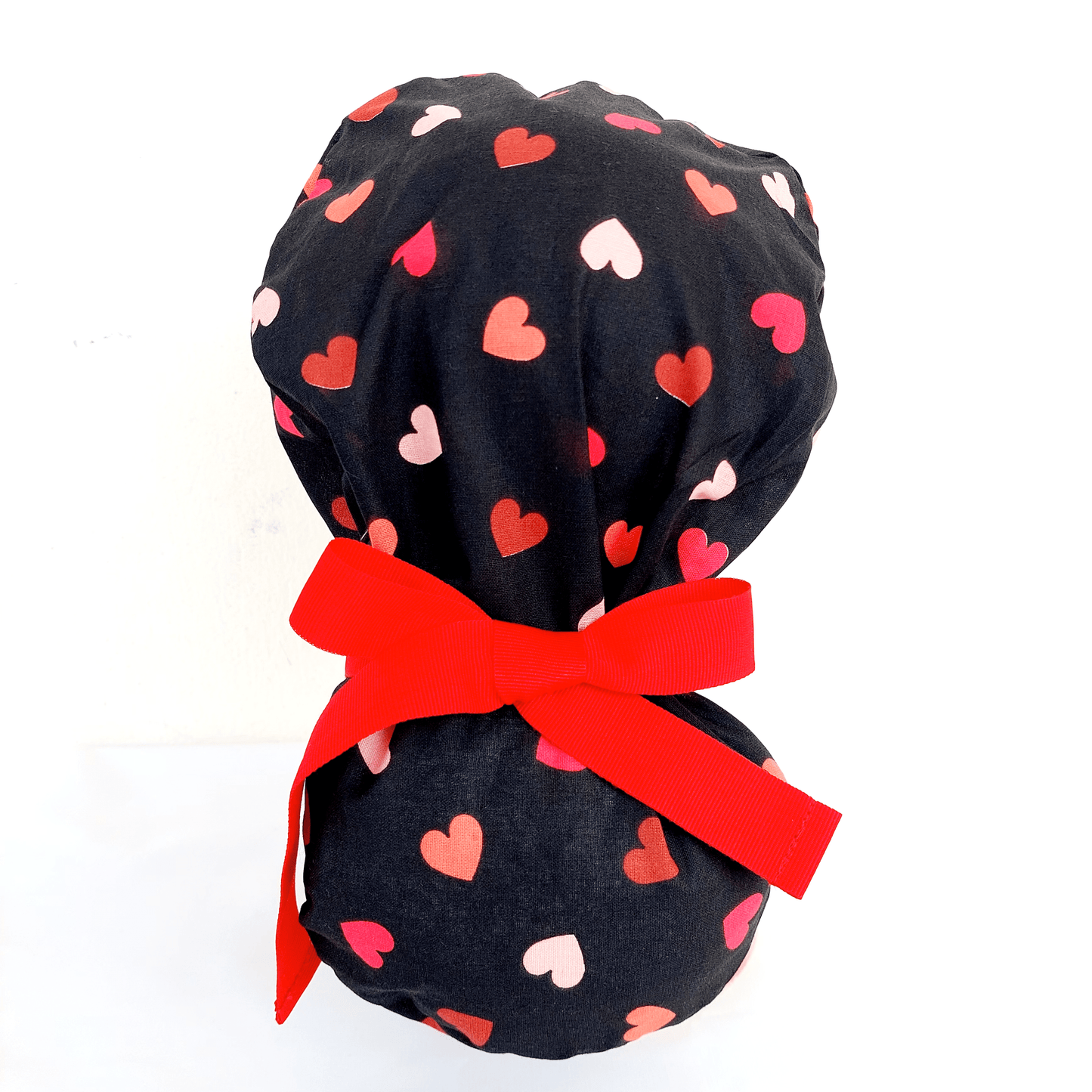 a doll head wearing scrub cap with a ponytail  pounce , red and pink hearts with red ribbons