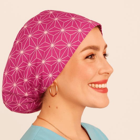 a woman wearing  apink scrub cap with abstract asanoha cotton print, the style is euro scrub hat its adjustable and she is smilling .