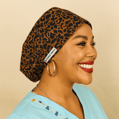 leopard scrub cap for women , the women on the photo is black and she is smiling 