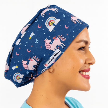 a woman wearing a scrub cap blue with pink unicorns on it and rainbows , the hat is cotton surgical cap euro style and can be embroideed with her name 